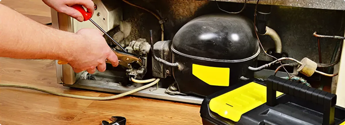Refrigerator repair technician fixing the compressor and wiring in Redmond, WA